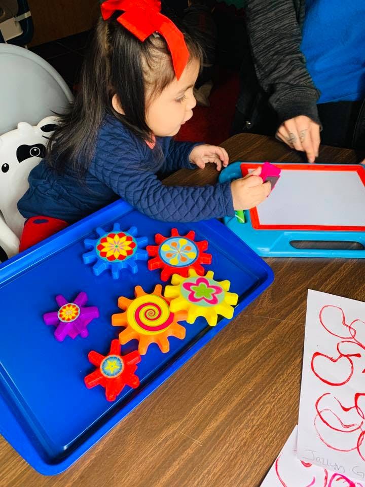 Child playing with colorful gears and a magnetic drawing board