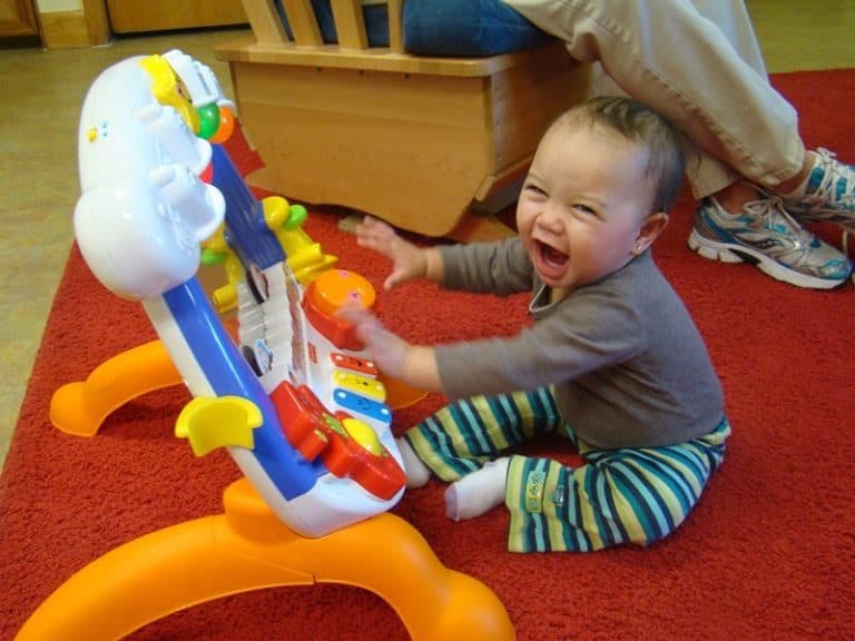 Child playing with a colorful activity toy on a red carpet