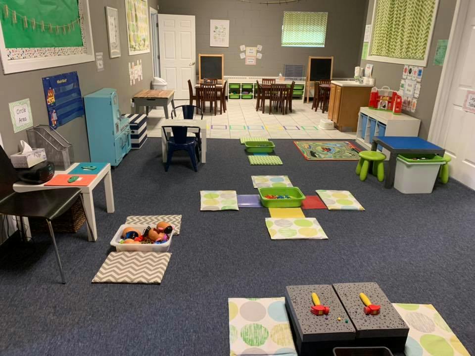 Classroom with small tables and chairs, and floor mats arranged in a path