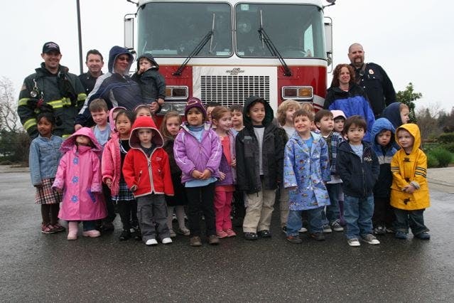 Adults and children standing in front of a fire truck