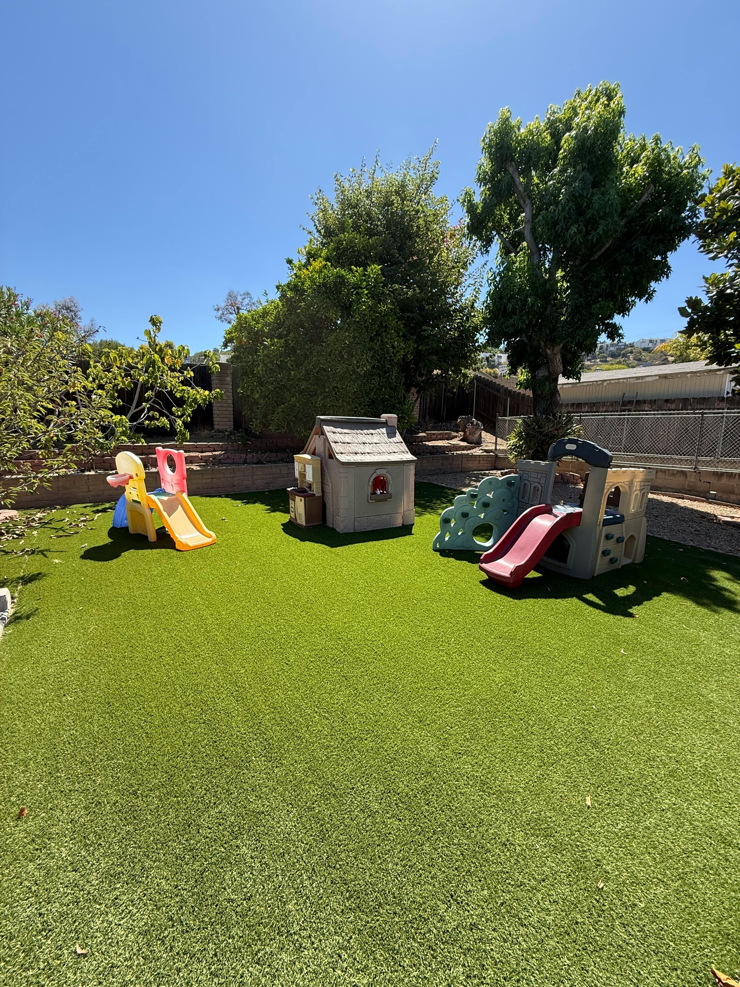 Plastic playhouses and slides on an artificial turf backyard
