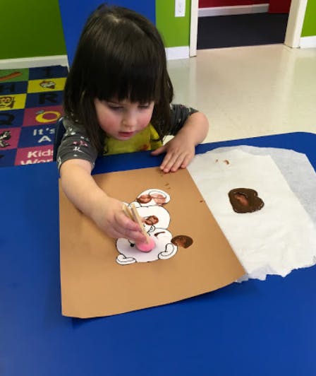 Child painting a snowman cutout with a sponge