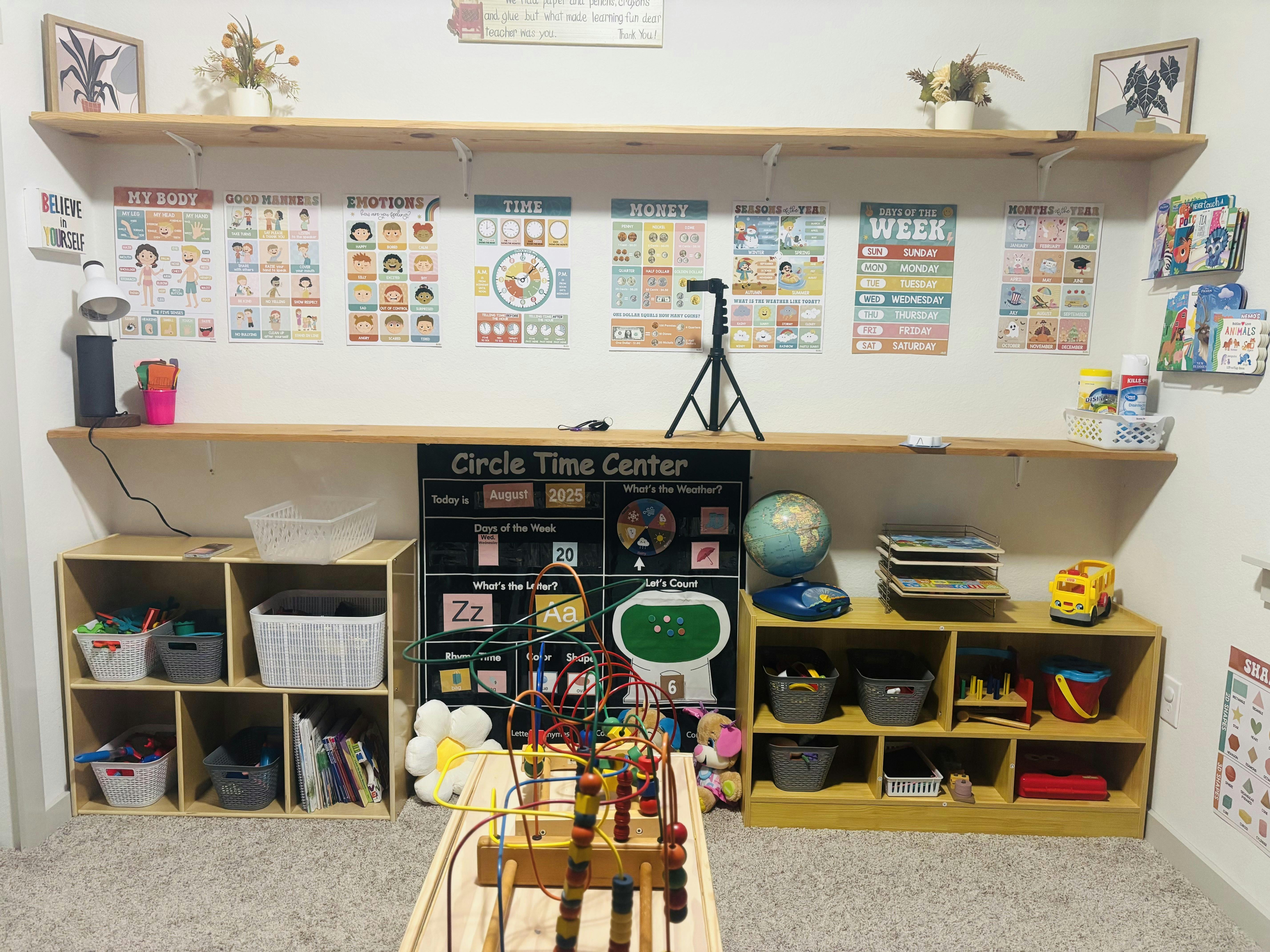Classroom wall with educational posters, shelves with toys, and a circle time calendar