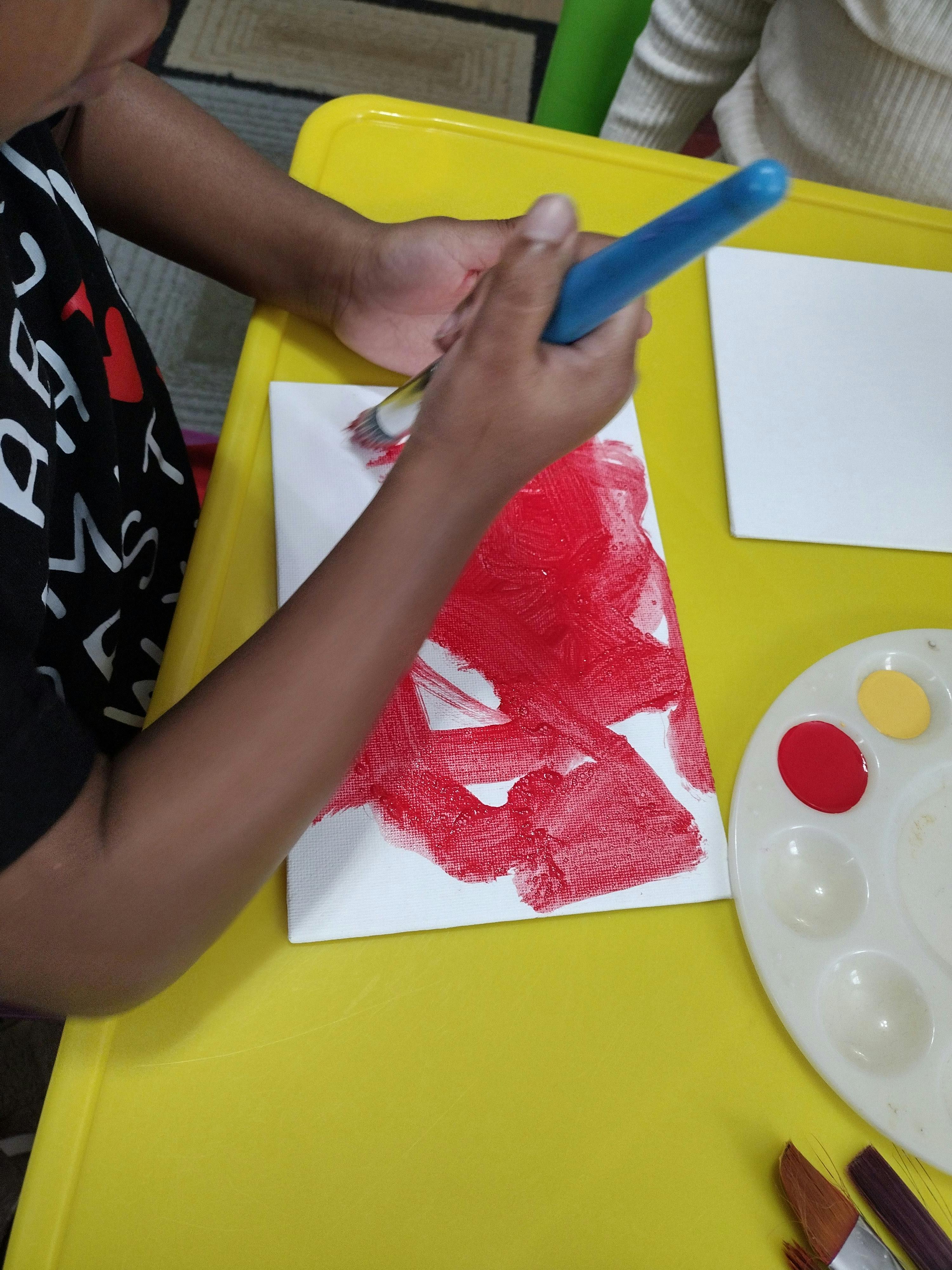 Person painting red on a white canvas with a paintbrush