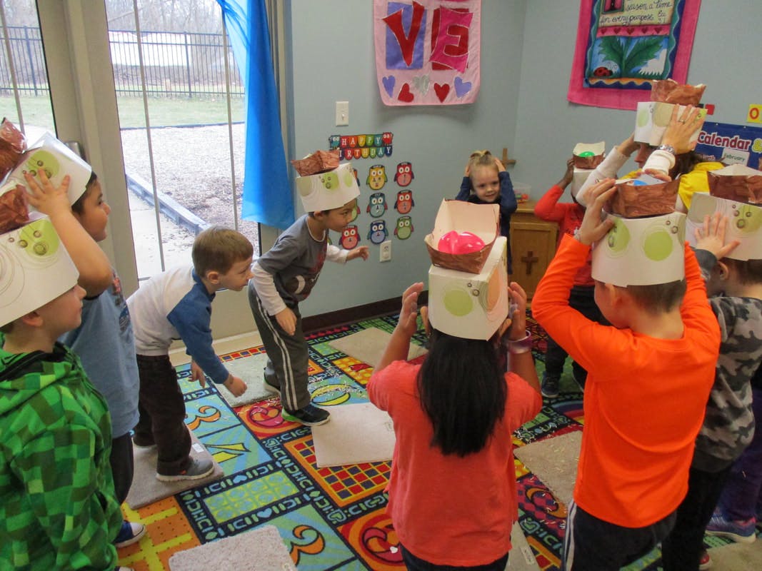 Children balancing objects on their heads in a classroom