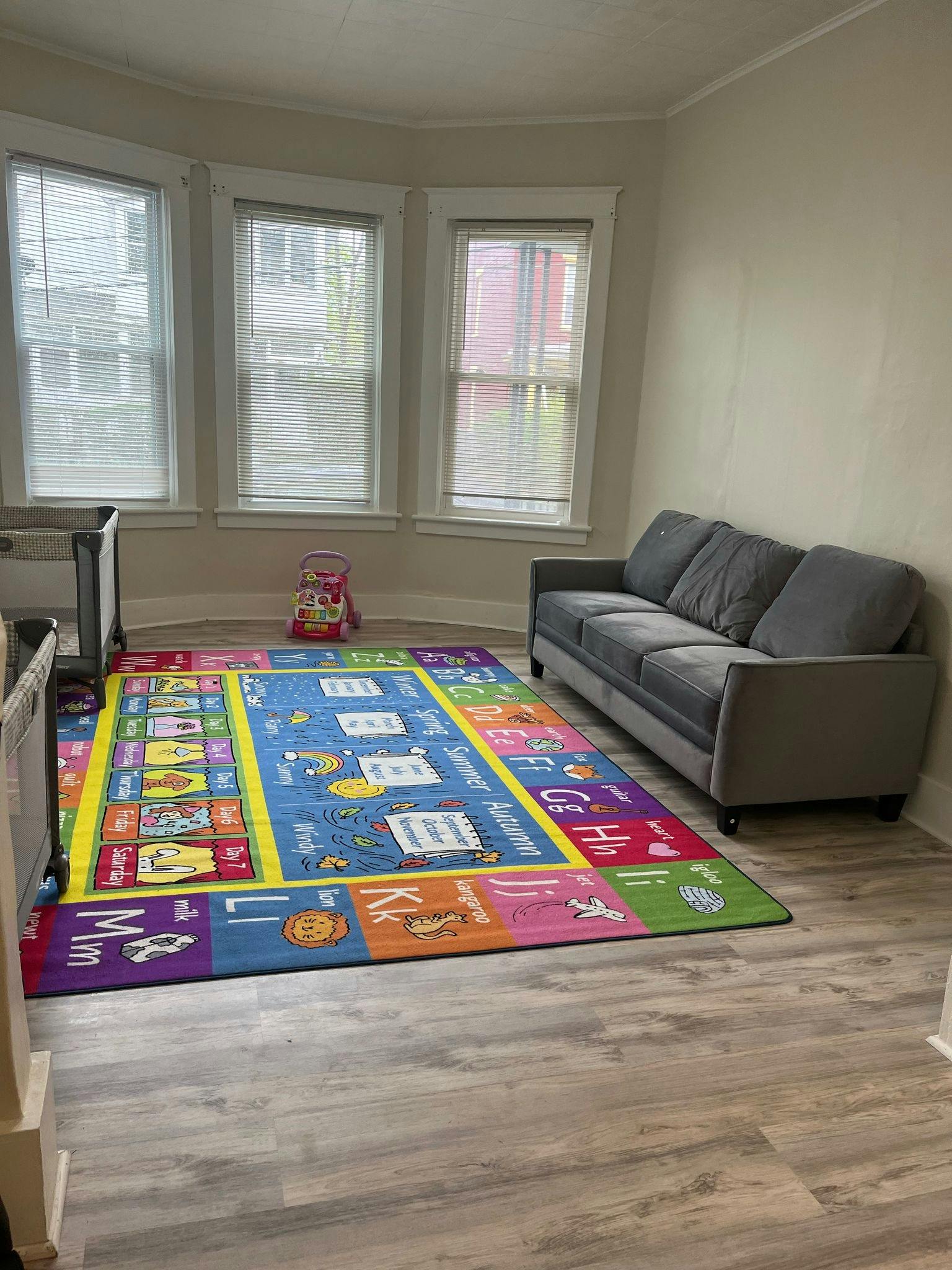 Living room with a gray sofa and a colorful alphabet rug