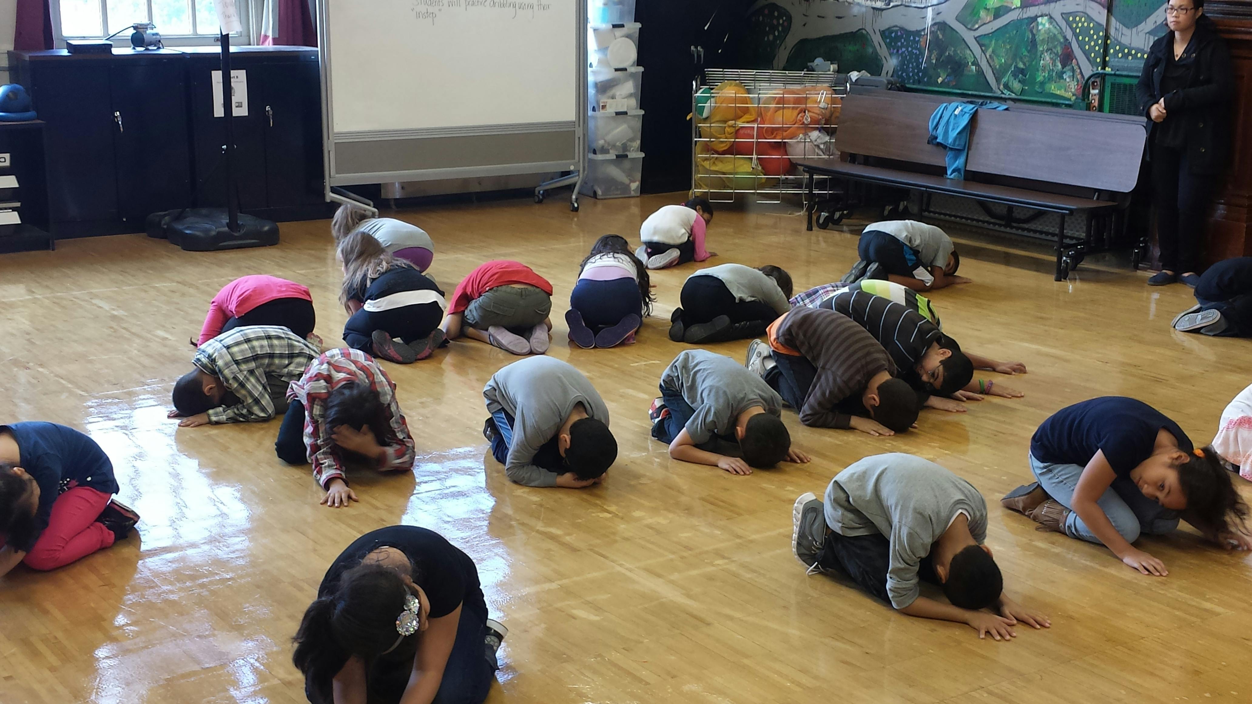 Many people bowing on a wooden floor
