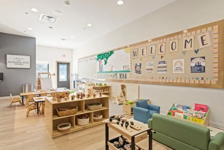 Classroom with a welcome sign, tables, chairs, and shelves with toys