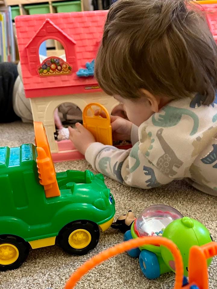 Child playing with a toy house on the floor