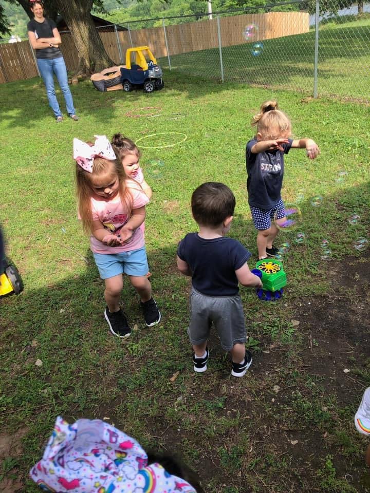 Children playing with bubbles in a grassy yard