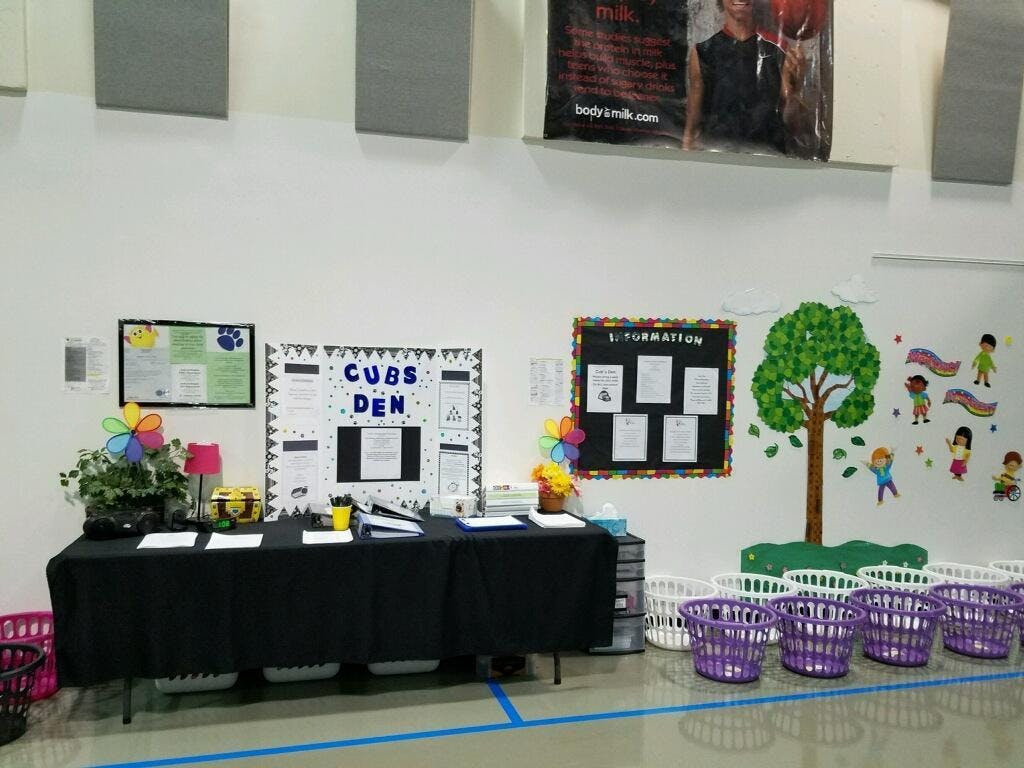 Table with "Cubs Den" sign and information boards on a wall