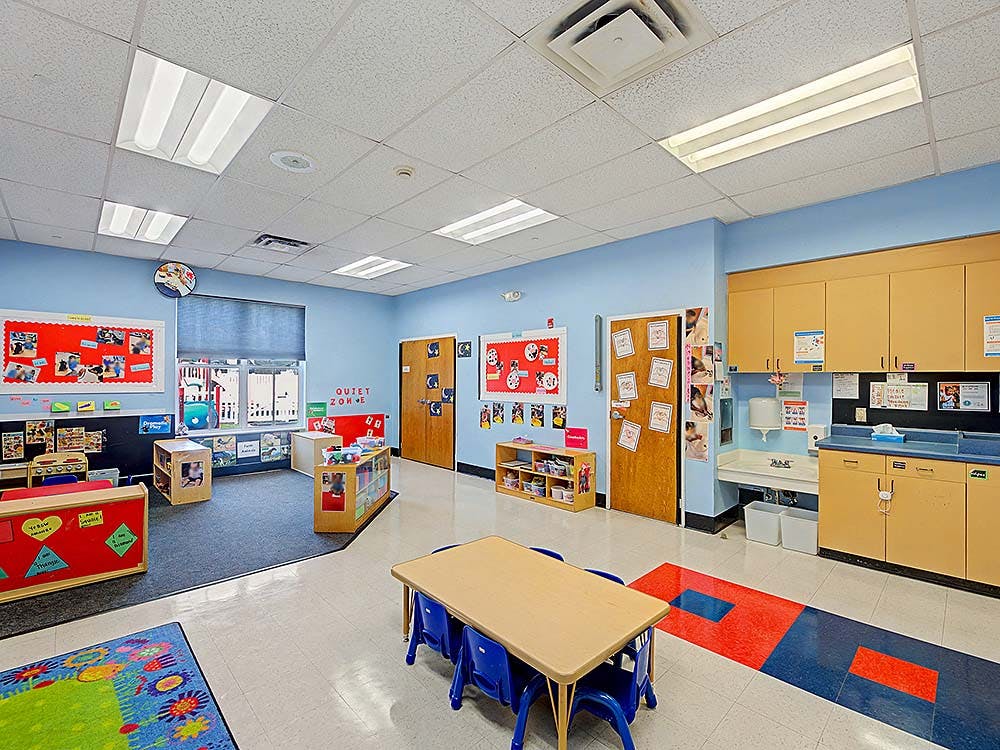 An empty classroom with light blue walls, various learning centers, and a sink
