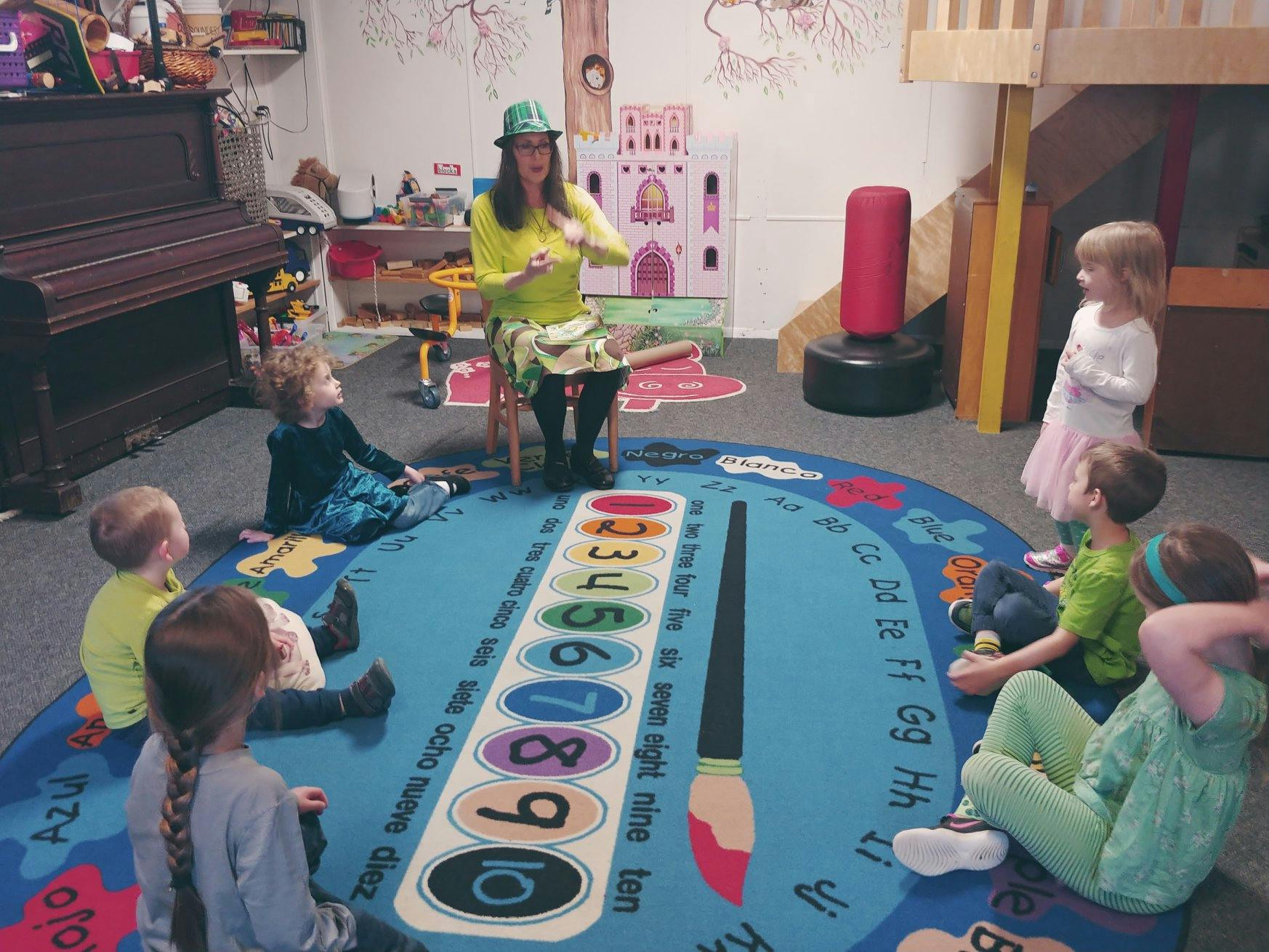 Person sitting on a chair with children sitting on a rug around them
