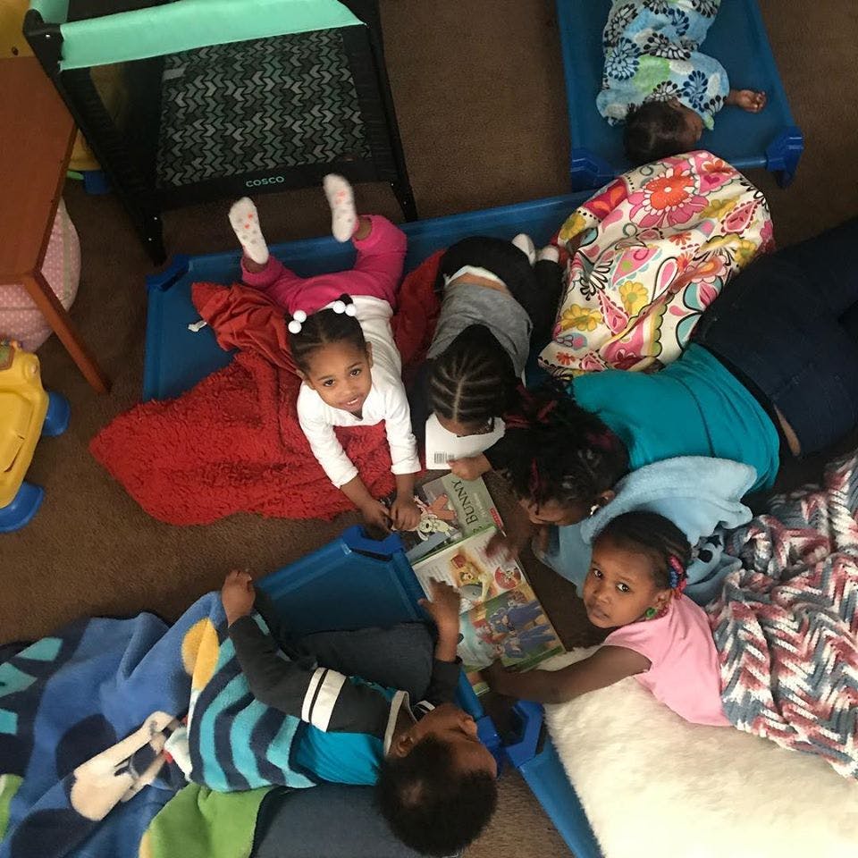 Children lying on cots looking at books