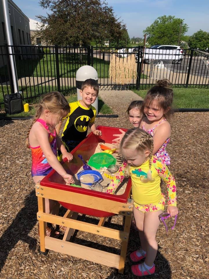 Children playing at a sand and water table outdoors