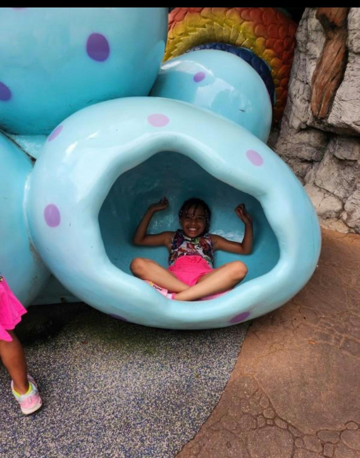 Child sitting inside a light blue, bean-shaped play structure