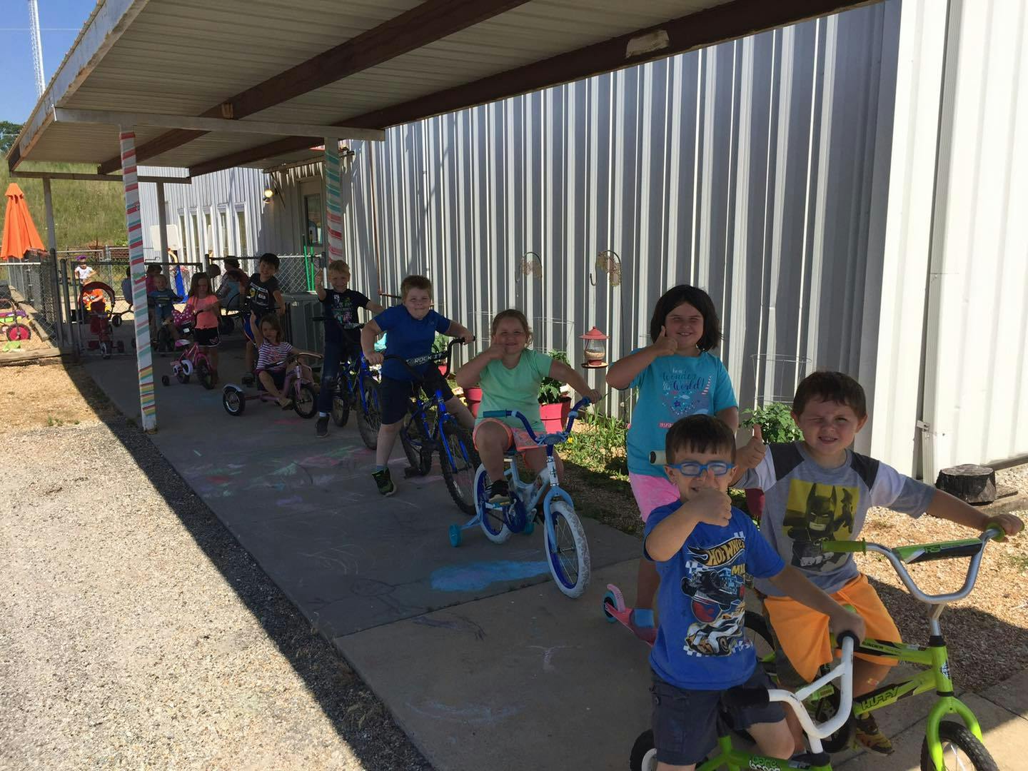Group of children on bicycles and tricycles under a covered walkway
