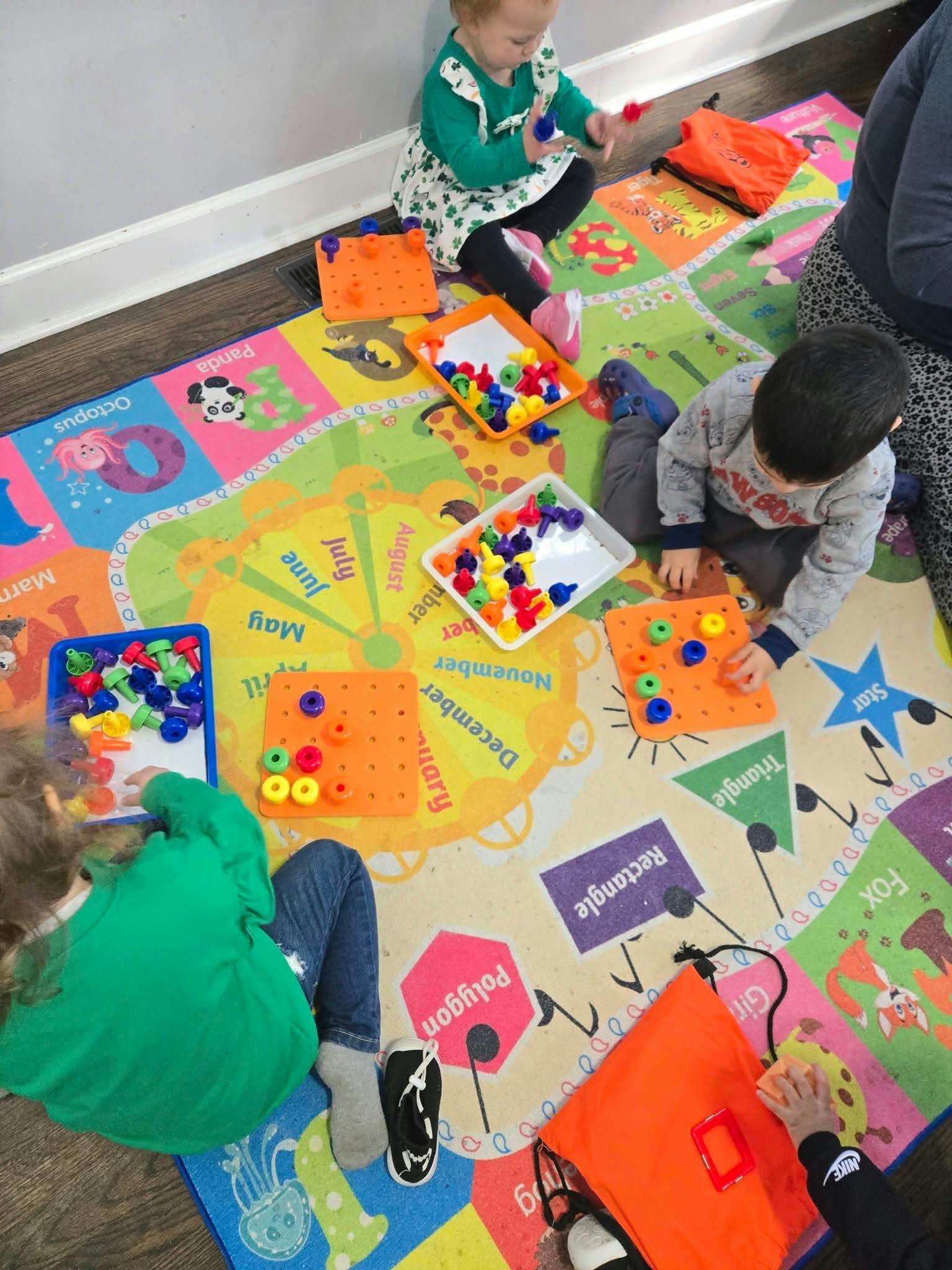 Children playing with colorful pegboard toys on a patterned floor mat