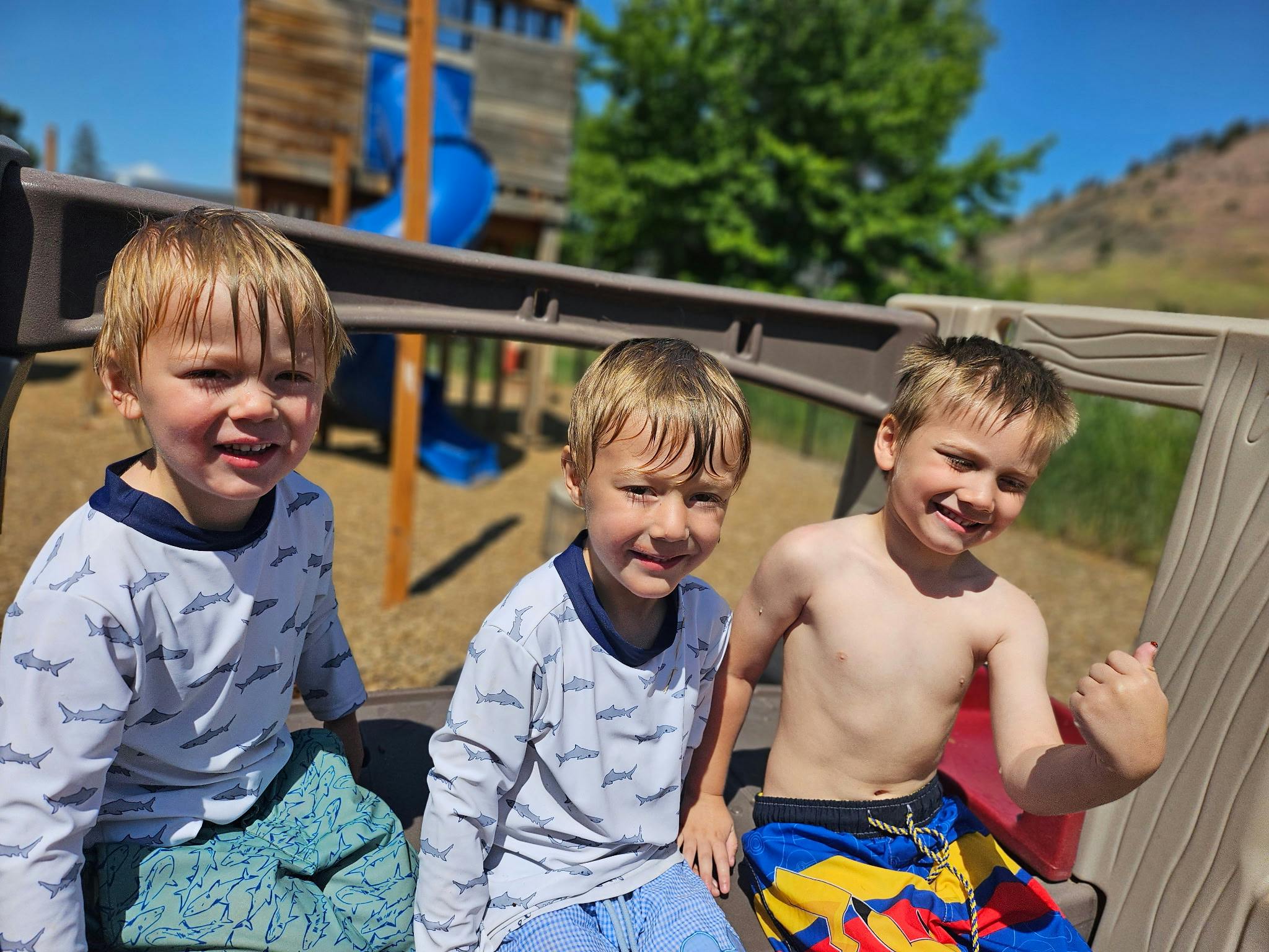 Three children sitting on a playground structure