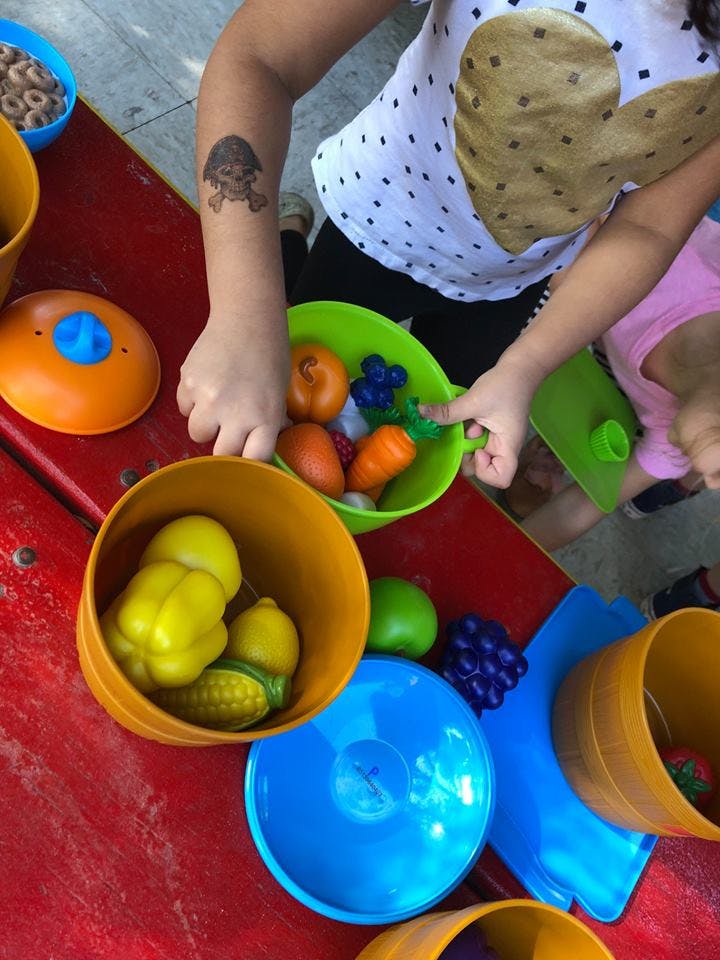 Child playing with toy fruits and vegetables in bowls