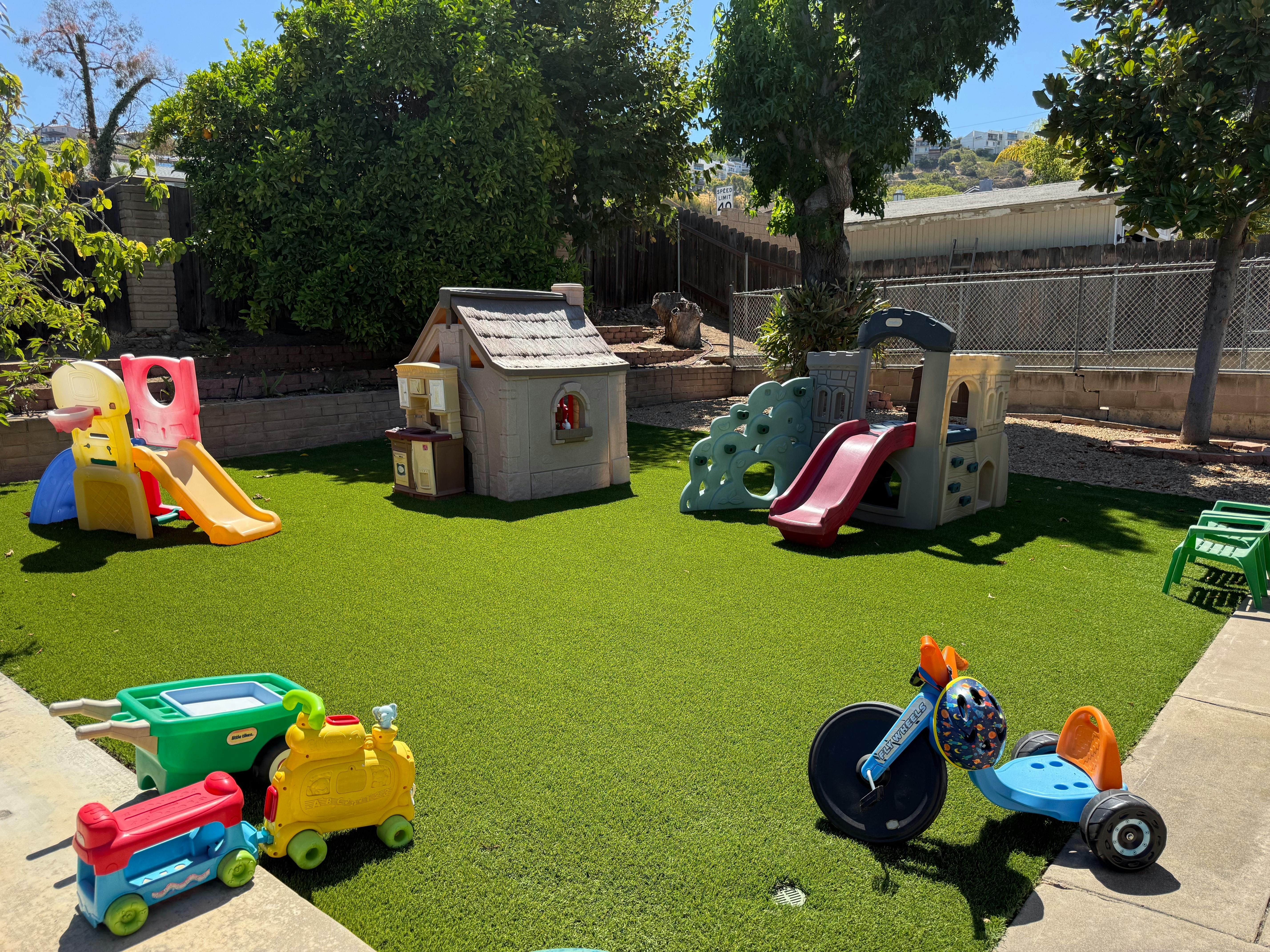 Plastic play equipment and toy vehicles on an artificial grass backyard