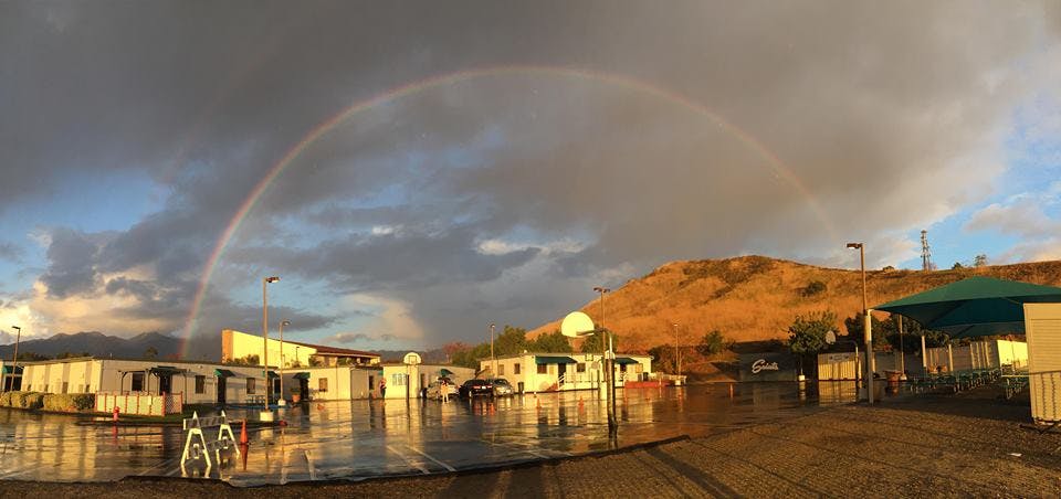 Rainbow over buildings and a flooded area with a hill in the background