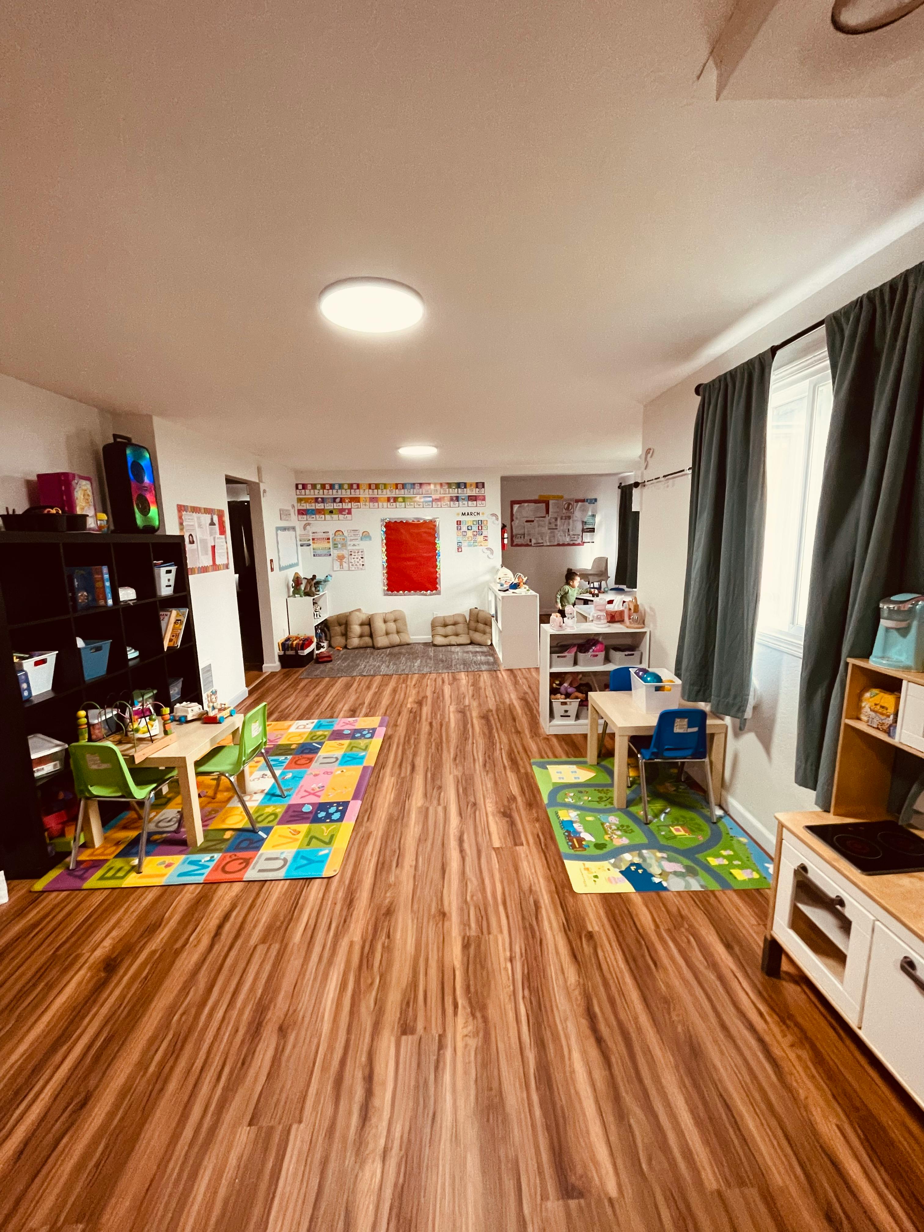 A classroom with colorful rugs, small tables, and chairs