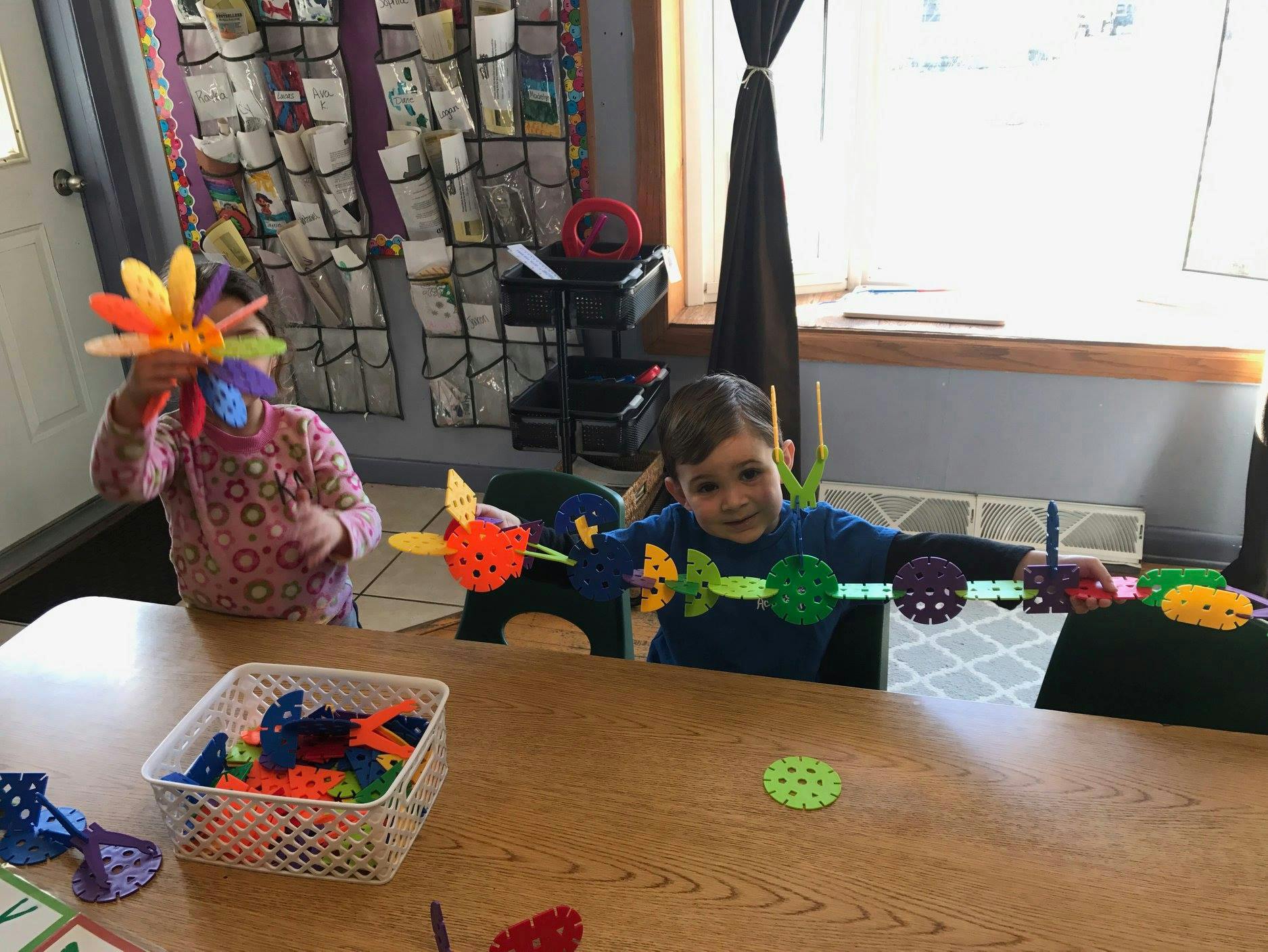 Two children playing with colorful interlocking toys at a table