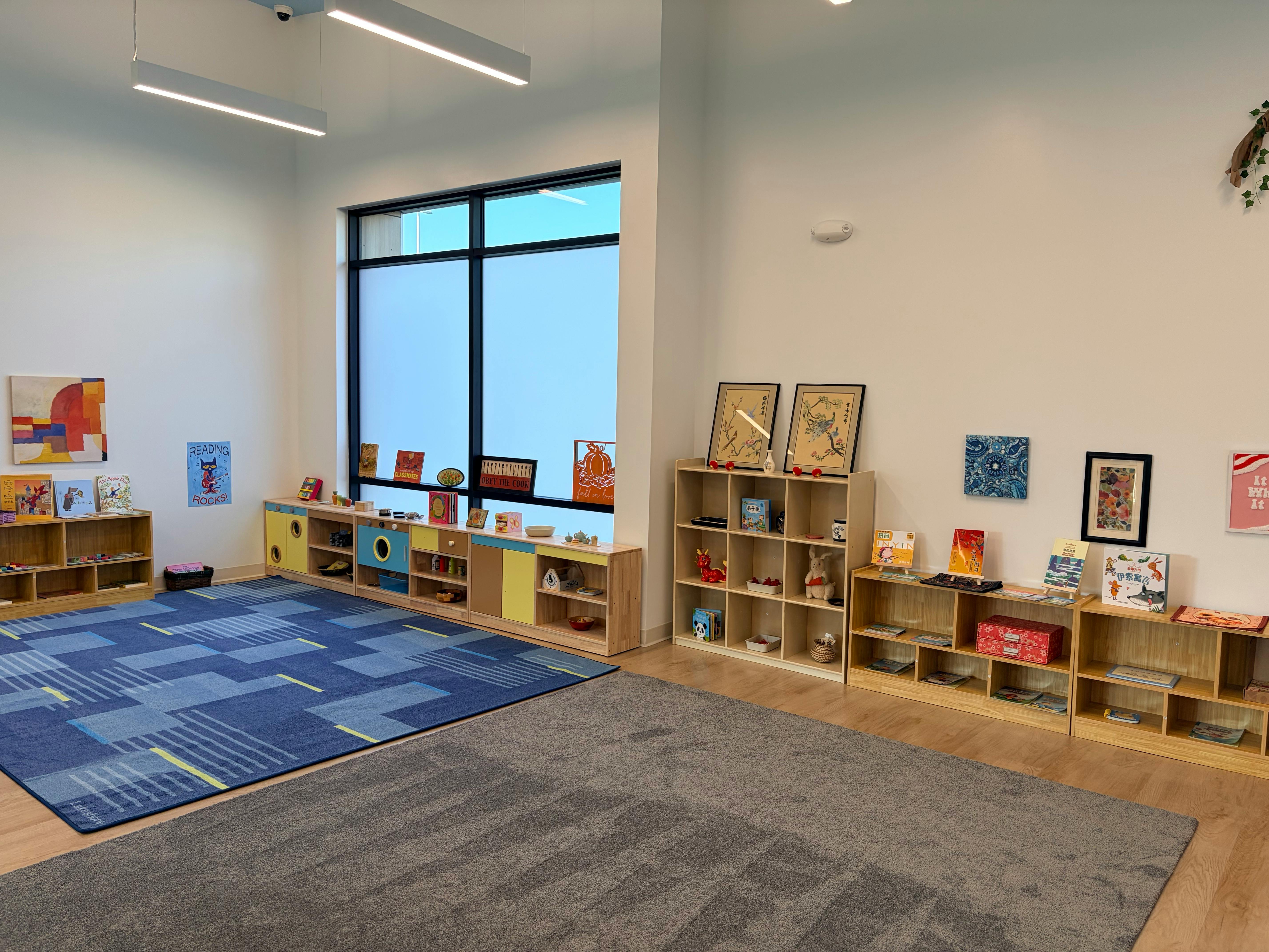 Classroom with bookshelves, colorful rug, window, and wall decorations