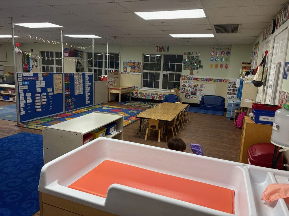 A classroom with a changing station in the foreground and a long wooden table