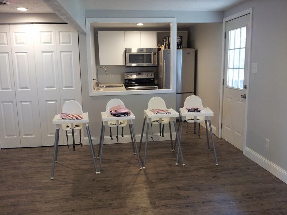 Four high chairs in a room with a kitchen in the background