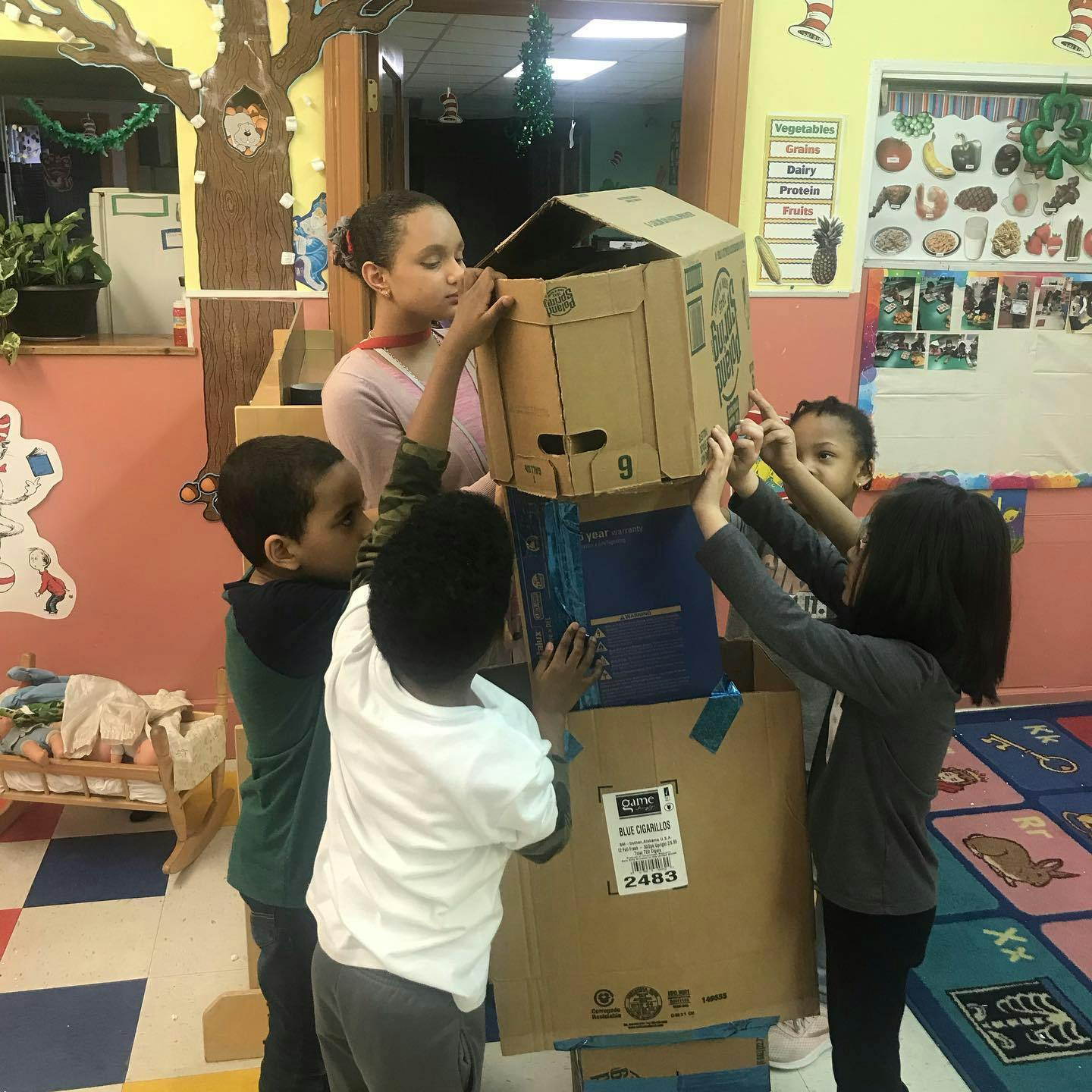 Person and children building a structure with cardboard boxes