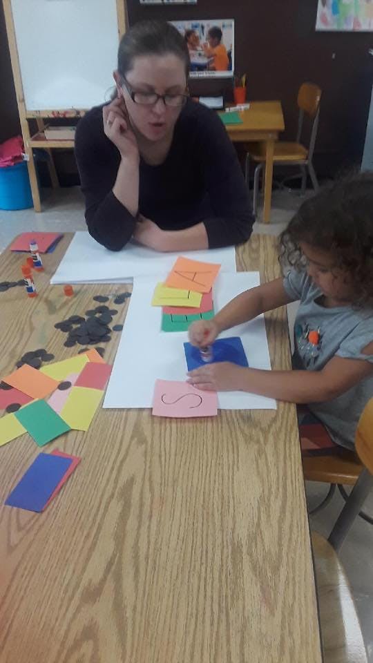 Person and child at a table with colorful paper and craft supplies