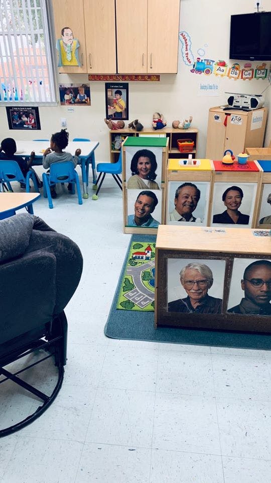 Children sitting at tables in a classroom with photos of adults on display