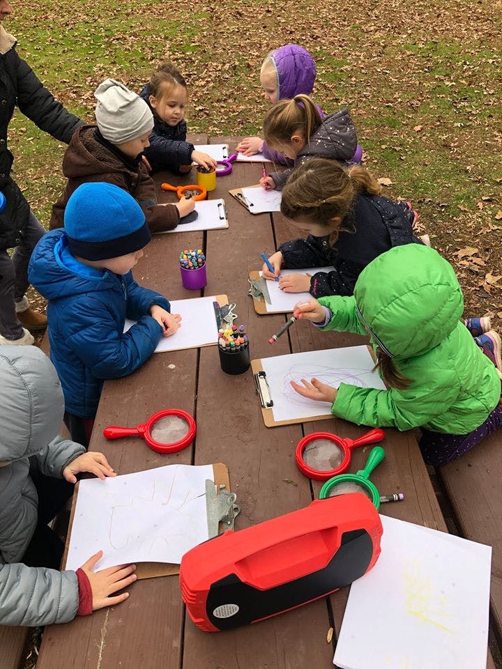 Children drawing at a picnic table outdoors
