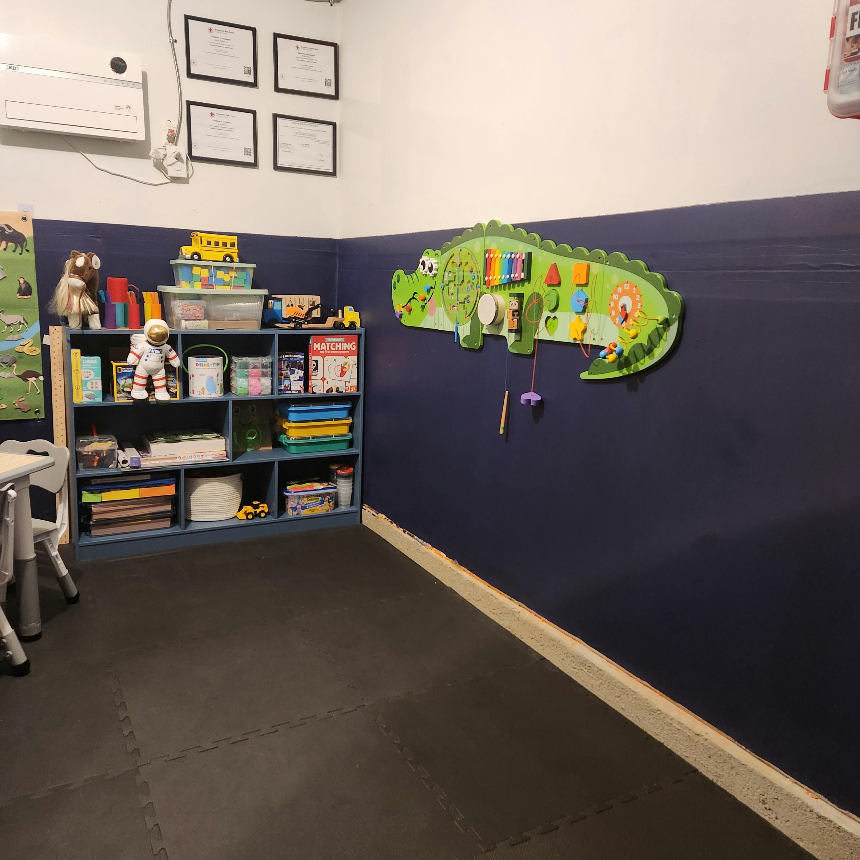 Alligator wall activity board and toy storage shelf in a playroom