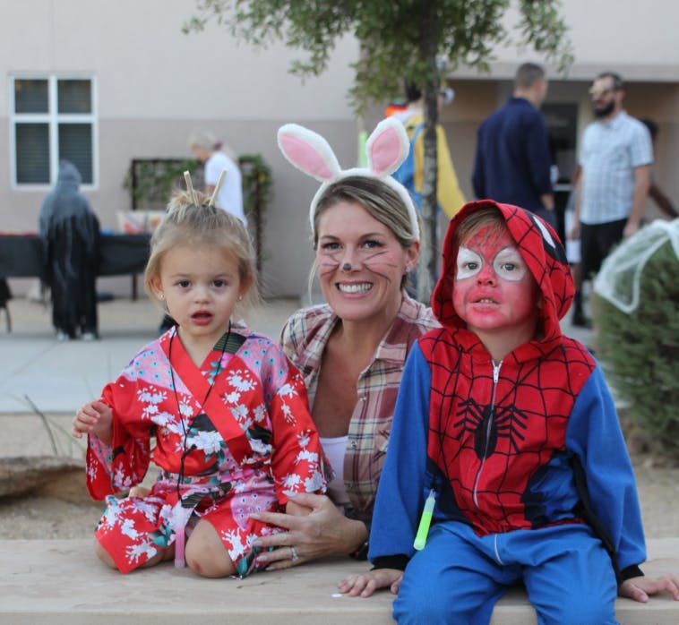 Person with bunny ears and two children in costumes