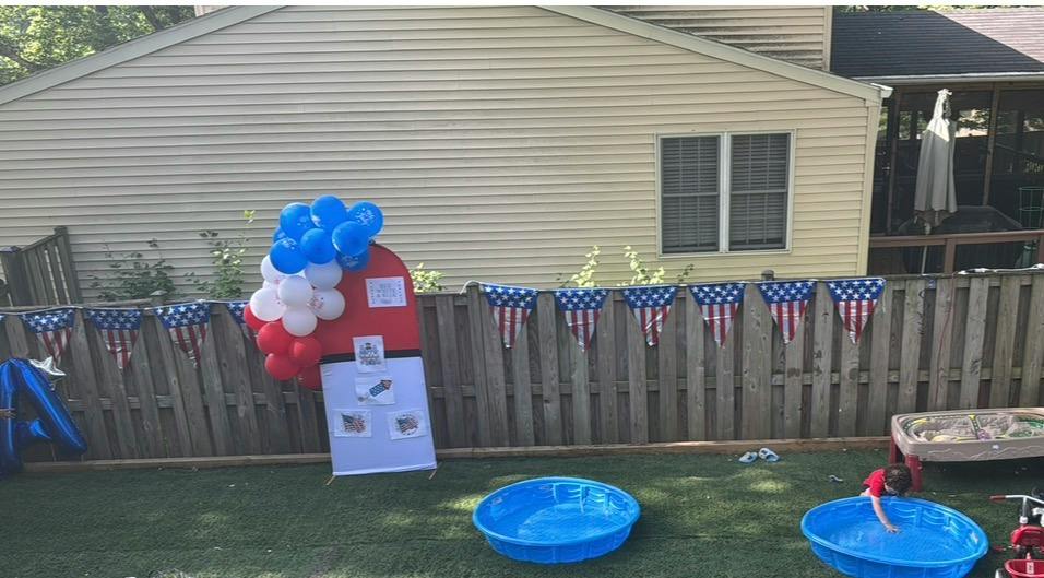 Child playing in a plastic pool in a backyard with patriotic decorations