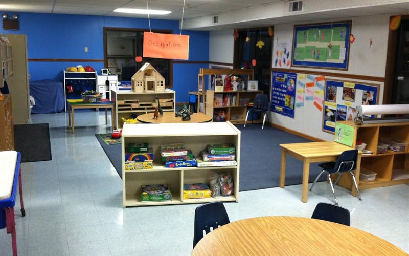 Classroom with play areas, tables, chairs, and learning materials on the walls