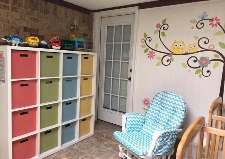 Nursery room with toy storage, rocking chair, and wall decal