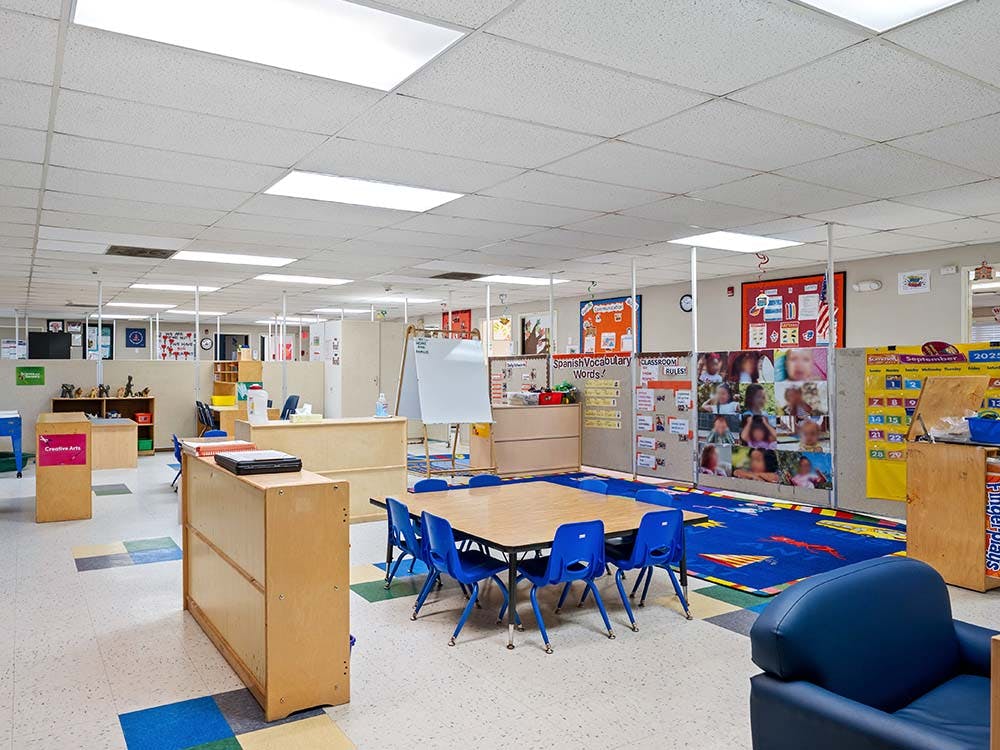 Empty classroom with tables, chairs, and learning materials