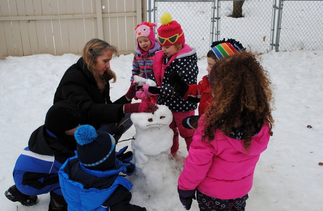 Person and children building a snowman in the snow