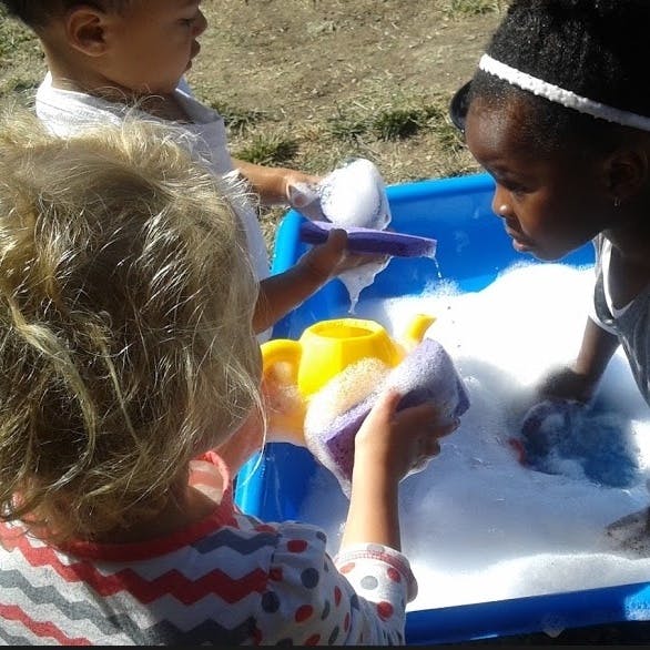 Children playing with soapy water in a blue tub