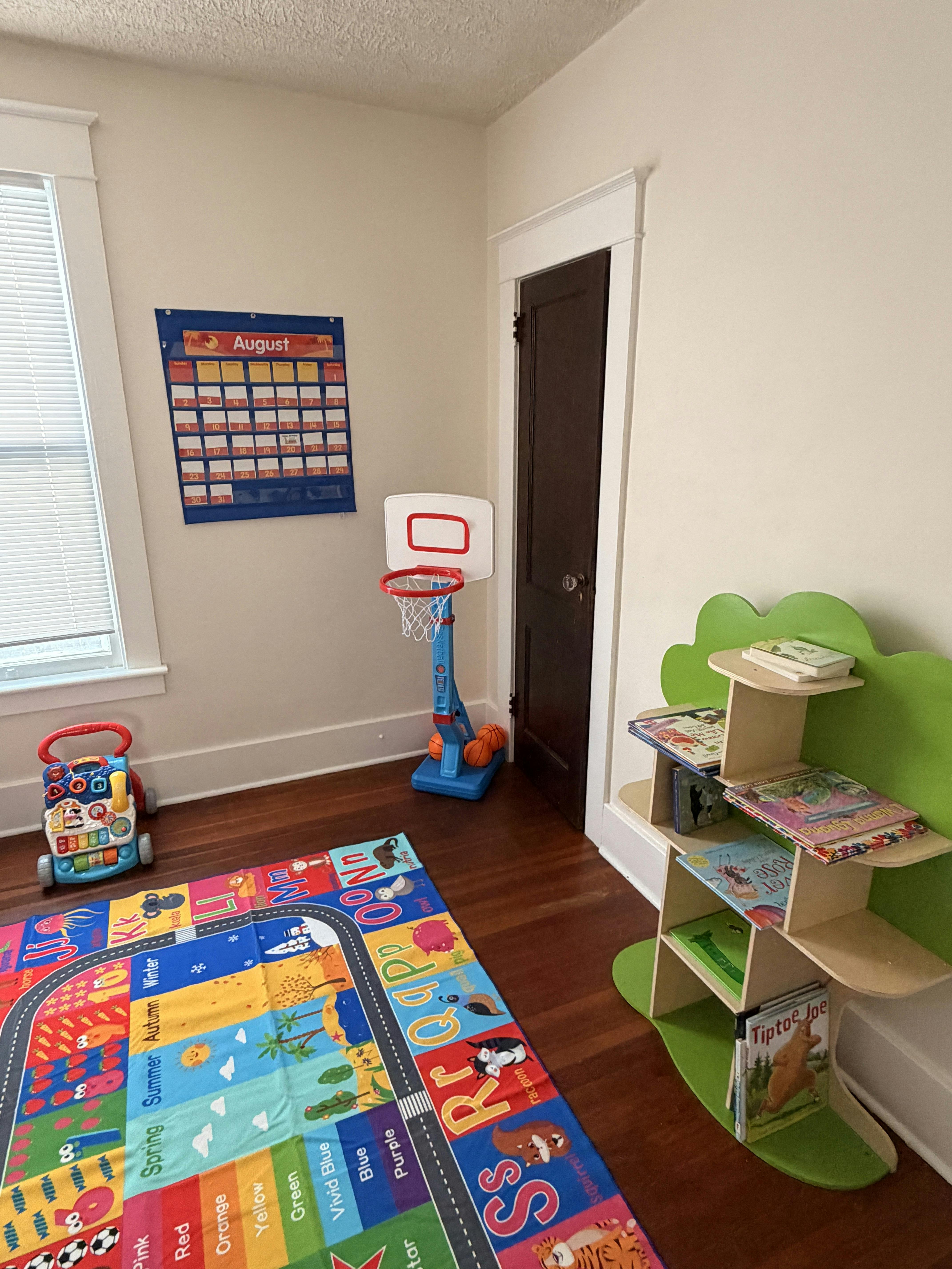 Playroom with a letter rug, toy basketball hoop, and a tree-shaped bookshelf