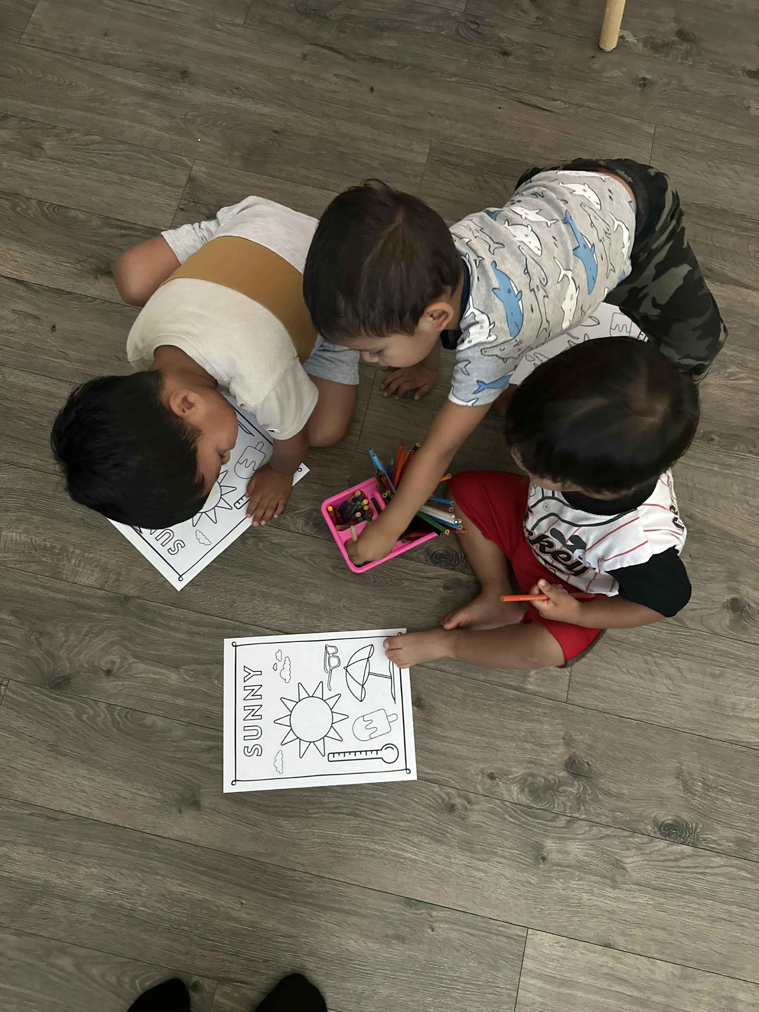 Three children coloring on the floor