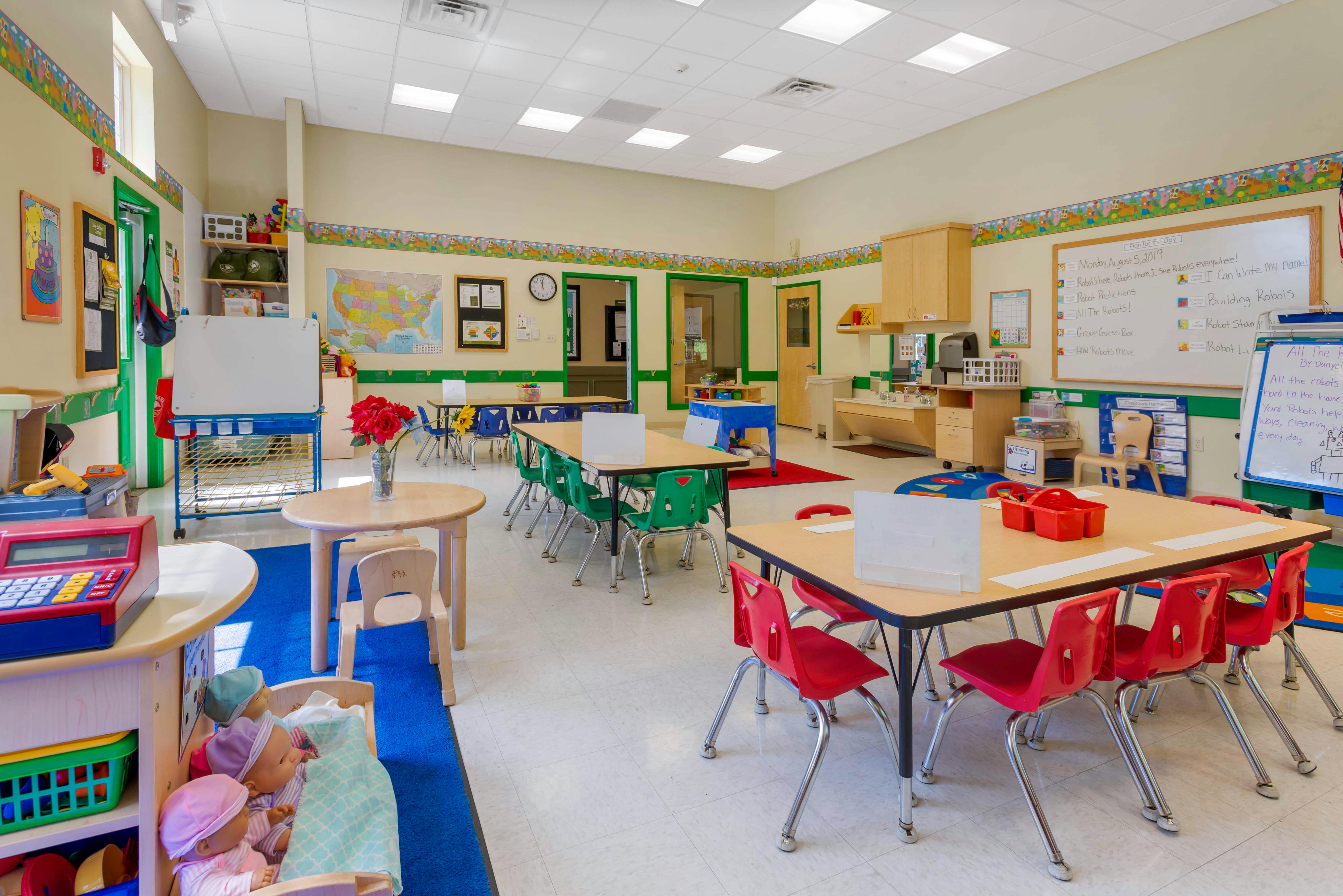 Classroom with small tables and chairs, whiteboards, and play areas