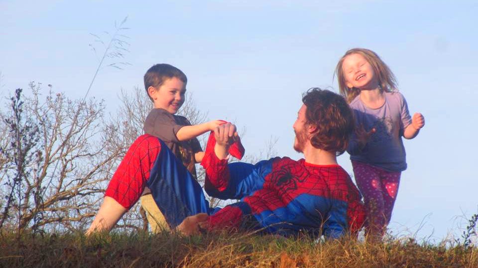 Person in costume playing with two children outdoors