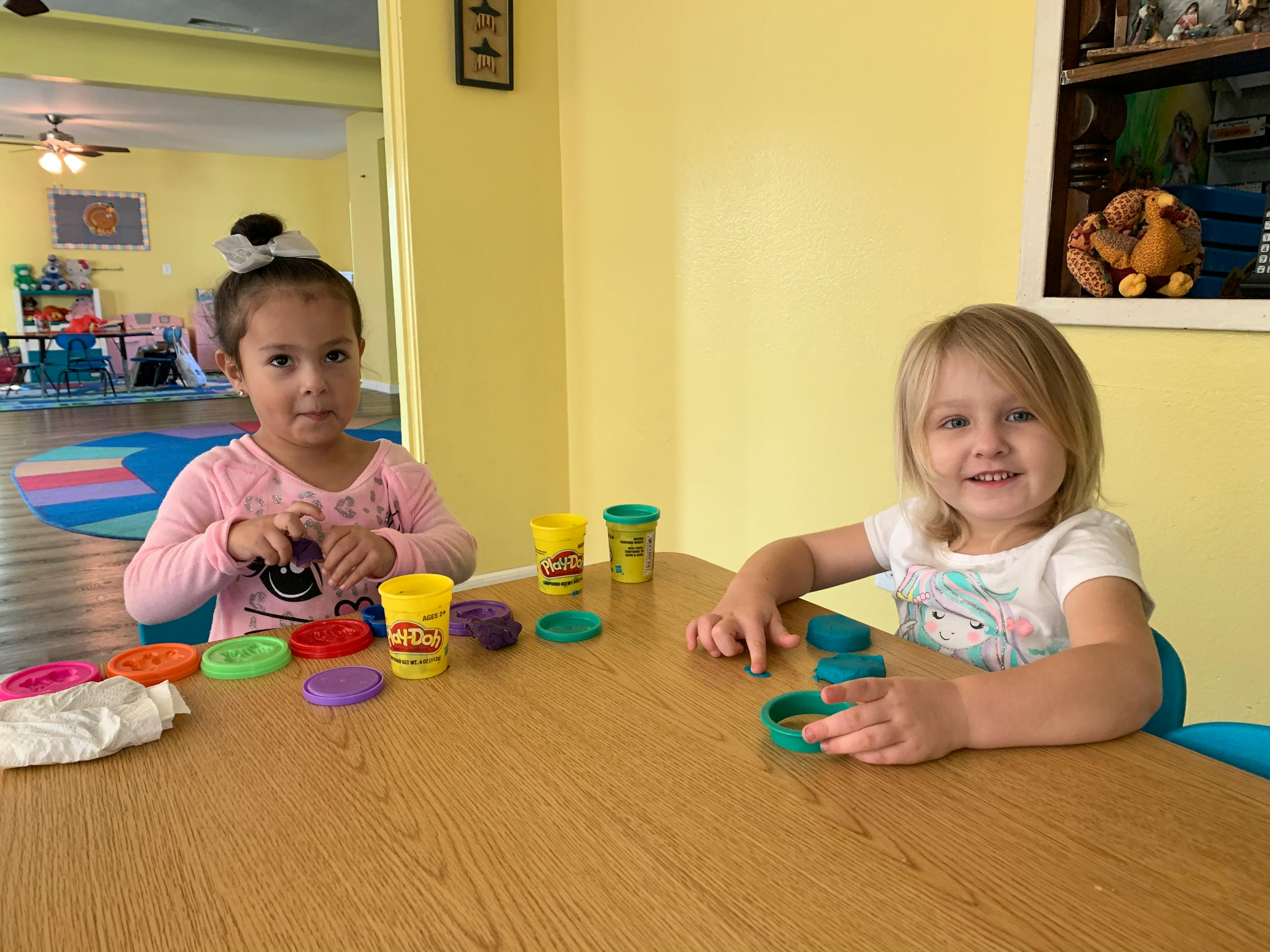 Two children playing with modeling clay at a table