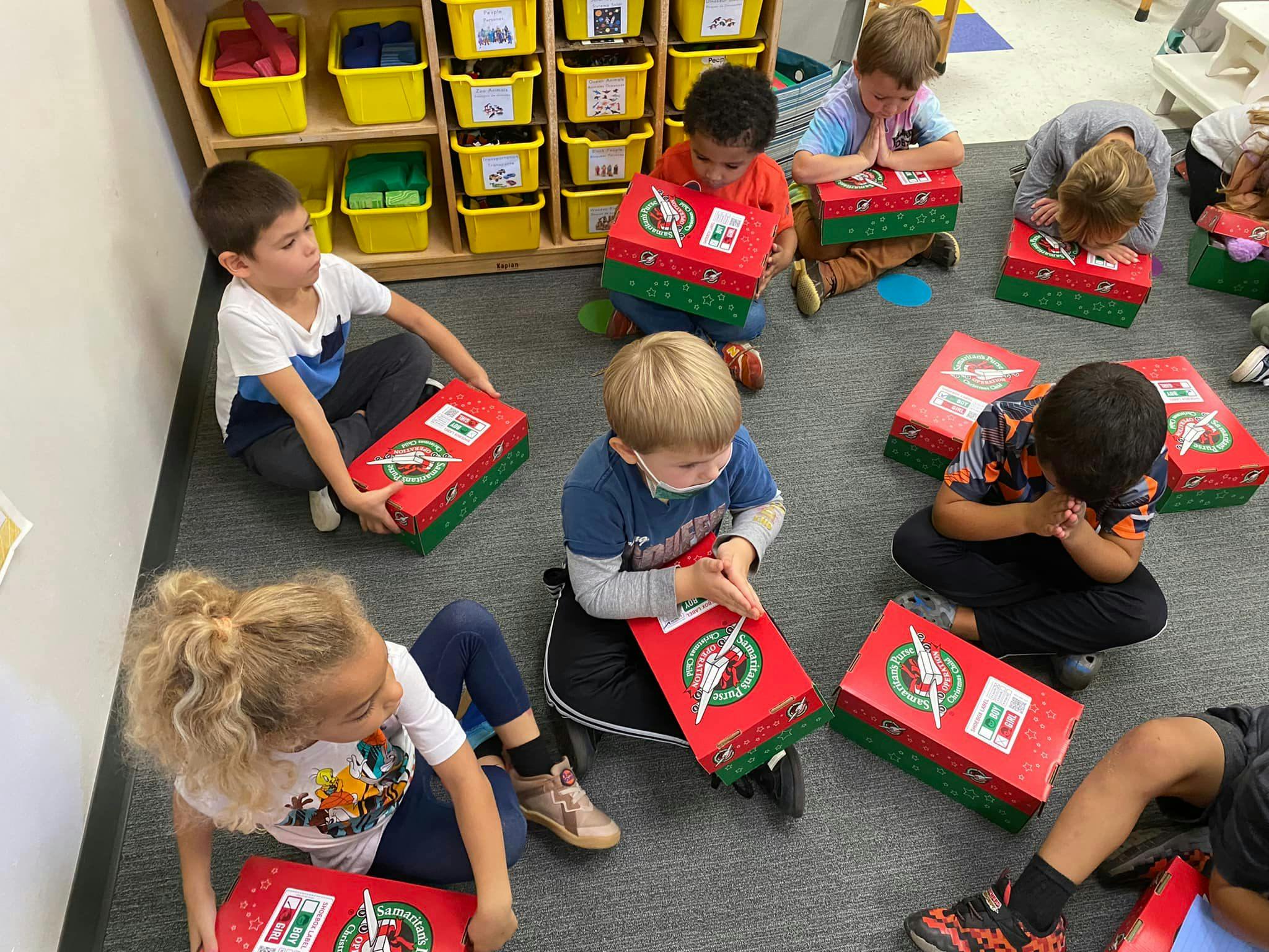 Children sitting on the floor with red and green boxes