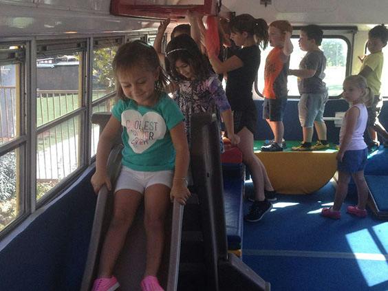 Child on a slide inside a bus with other children